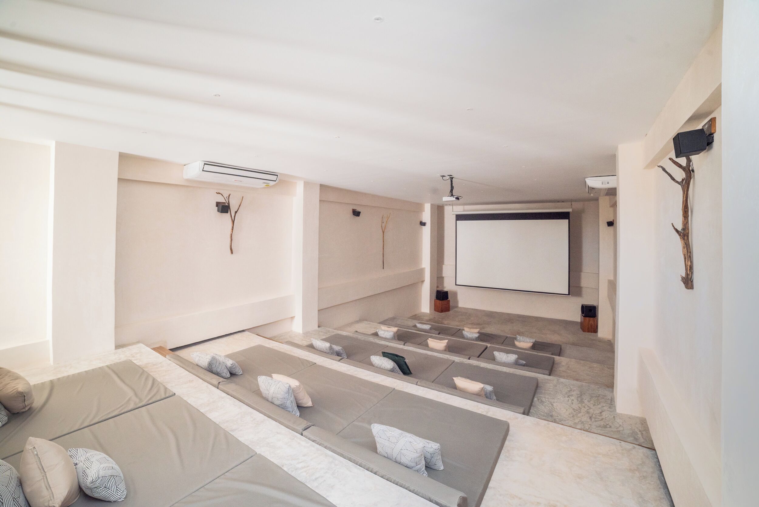 A modern home theater room with multiple seating areas, a large screen, and a projector.