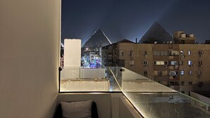 Un balcón con vista a un edificio en forma de pirámide, de noche.