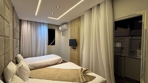 Un dormitorio moderno con dos camas, un televisor y un vestidor.
