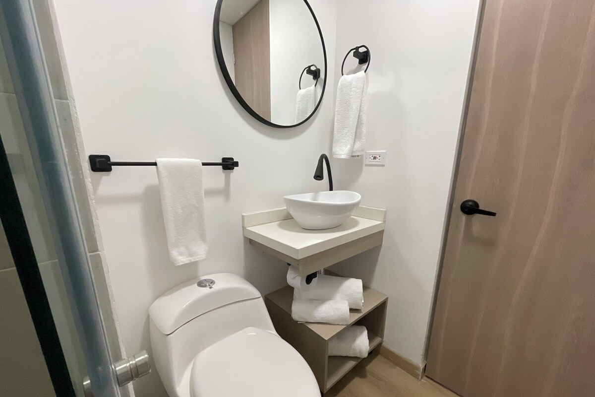 A bathroom with a toilet, sink, and mirror.