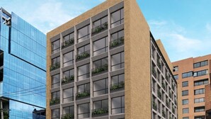 A modern building with a beige facade, multiple floors, and balconies with greenery. - Nova Iorque Suites by Avia Suites (Bogotá)