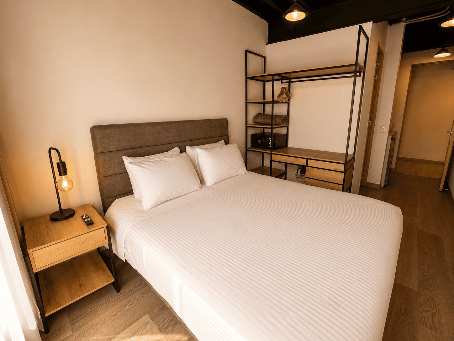 Un dormitorio con cama, mesita de noche, lámpara y un banco empotrado con espacio de almacenamiento.