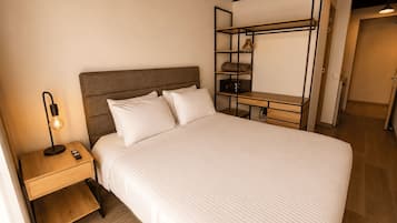 Un dormitorio con cama, mesita de noche, lámpara y un banco empotrado con espacio de almacenamiento.