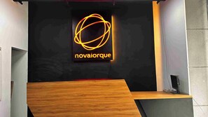 A reception desk with a neon sign reading 'novaiorque' and a wooden counter. - Nova Iorque Suites by Avia Suites (Bogotá)