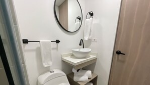 A bathroom with a toilet, sink, and mirror. - Nova Iorque Suites by Avia Suites (Bogotá)