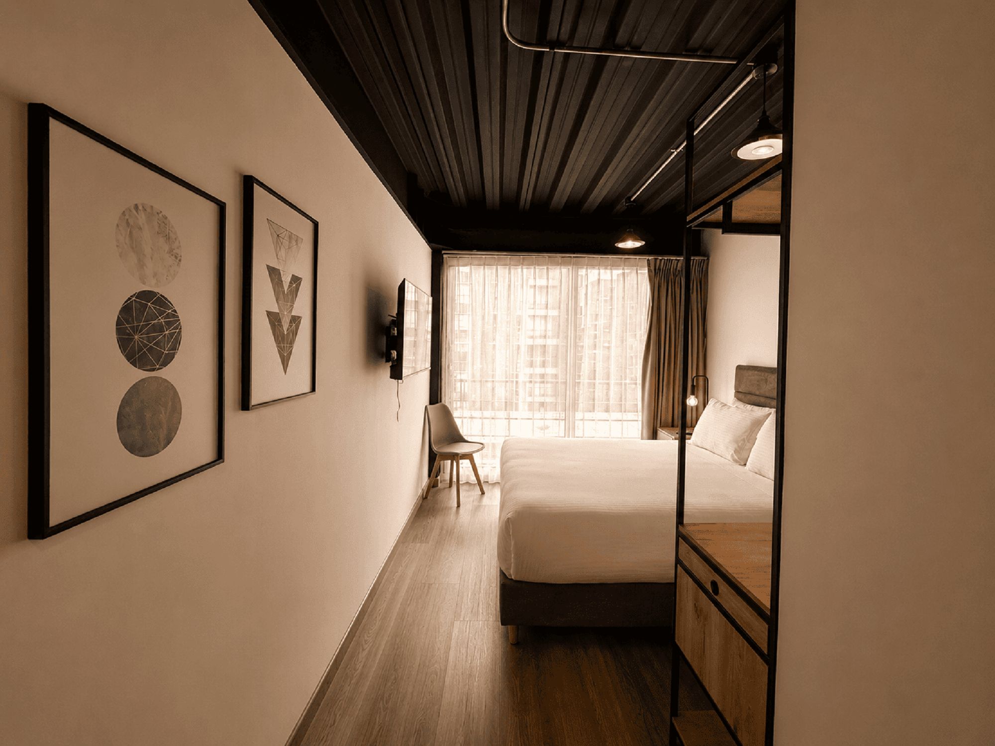Una habitación de hotel con una cama, una silla y obras de arte en la pared.