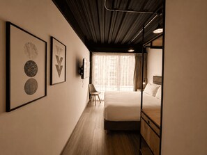 Una habitación de hotel con una cama, una silla y obras de arte en la pared.