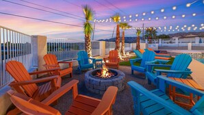 An outdoor seating area with Adirondack chairs, a fire pit, and string lights against a sunset sky. - The Desert Oasis- Pool, Spa, Game Room, Basketball, Pickleball (Lake Havasu City)