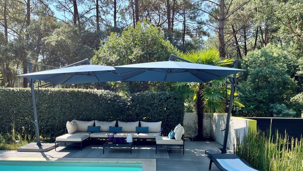 A poolside area with a covered seating area, a pool, and surrounding greenery. - Villa Hortensia - Welkeys (Soorts-Hossegor)
