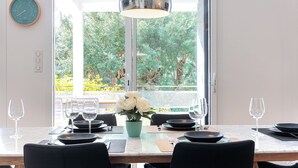 A dining area with a table set for four, a potted plant, and a view of greenery outside. - Villa Hortensia - Welkeys (Soorts-Hossegor)
