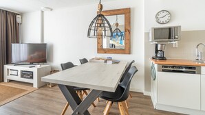 Een moderne keuken met een houten tafel, zwarte stoelen, een magnetron en een vaatwasser.