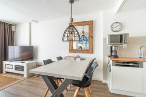A modern kitchen with a wooden table, black chairs, a microwave, and a dishwasher.
