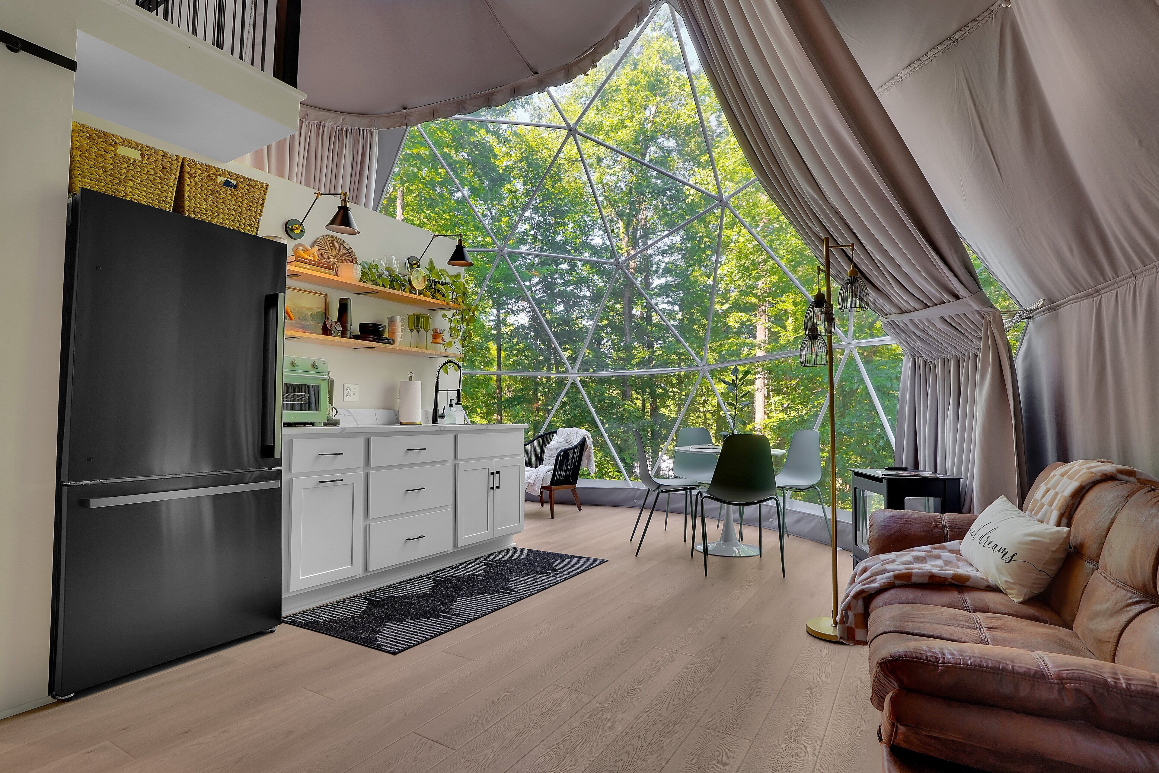 Eine moderne Küche mit Kühlschrank, weißen Schränken und einer Essecke mit Tisch und Stühlen.