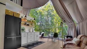 Una cocina moderna con refrigerador, gabinetes blancos y un comedor con mesa y sillas.