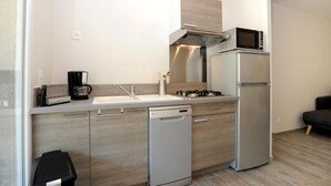 Una cocina compacta con lavavajillas integrado, cocina a gas, microondas y refrigerador.