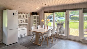 Een keuken met een eettafel, stoelen, een koelkast en een inbouwkast.