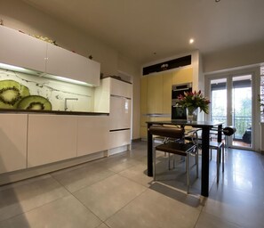 Una cocina moderna con armarios blancos, una mesa de comedor con sillas y un ventanal con vistas a zonas verdes.