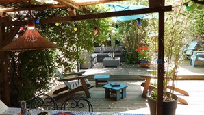 An outdoor patio with a wooden deck, a covered seating area, and string lights.