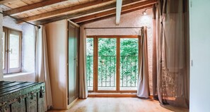 Una stanza con soffitto in legno, un'ampia finestra vista su del verde e una porta.