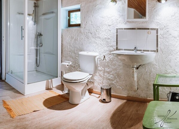 Un bagno con box doccia in vetro, un water, un lavandino e una piccola finestra.