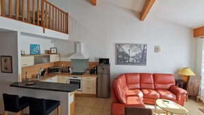 A modern living space with a kitchen, a dining area, and a seating area with a sofa and armchairs.