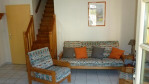 Ein Wohnzimmer mit einer Holztreppe, einem gemusterten Sofa und einem Sessel.