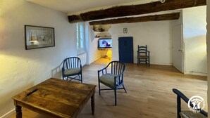 Une pièce spacieuse avec une table en bois et deux chaises, un téléviseur en arrière-plan et une porte bleue.