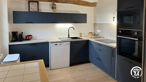 Une cuisine moderne avec des meubles de couleur bleu foncé, un lave-vaisselle, un évier et un four encastré.