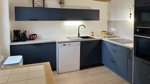 A modern kitchen with dark blue cabinets, a dishwasher, a sink, and a built-in oven.