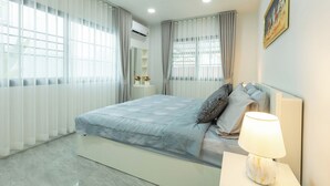 A modern bedroom with a bed, a nightstand, a lamp, and a painting on the wall.