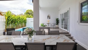 A patio with a marble table and chairs, a small pool, and potted plants.