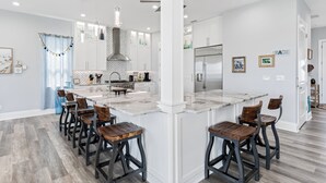 Une cuisine moderne dotée d’un grand îlot central, de tabourets de bar et d’un coin repas.