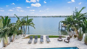 Un espace aménagé au bord de la piscine, avec des chaises longues et une vue sur une étendue d’eau calme.