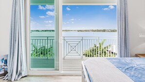 Une chambre avec un balcon donnant sur un paysage magnifique, avec un lac et des bâtiments situés au loin.