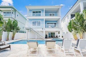 Una casa de dos pisos con piscina, zona de estar exterior y una escalera que conduce al piso superior.