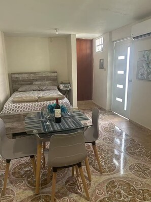 A bedroom with a bed, a bedside table, and a small table with a bottle and glasses.