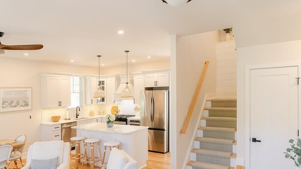 Una cocina moderna con armarios blancos, una isla central y electrodomésticos de acero inoxidable.