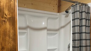 Une cabine de douche blanche avec une barre métallique et un rideau de douche à carreaux.