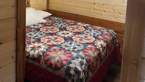 Une chambre confortable avec un plafond en bois et un toit en pente, comprenant un lit recouvert d’une courtepointe aux couleurs vives et un ventilateur de plafond.