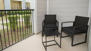 Ein Balkon mit zwei Korbstühlen und einem kleinen Tisch.