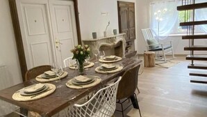 Zona de menjador amb una taula llarga preparada per a sis, envoltada de cadires blanques amb un disseny d'entramat.