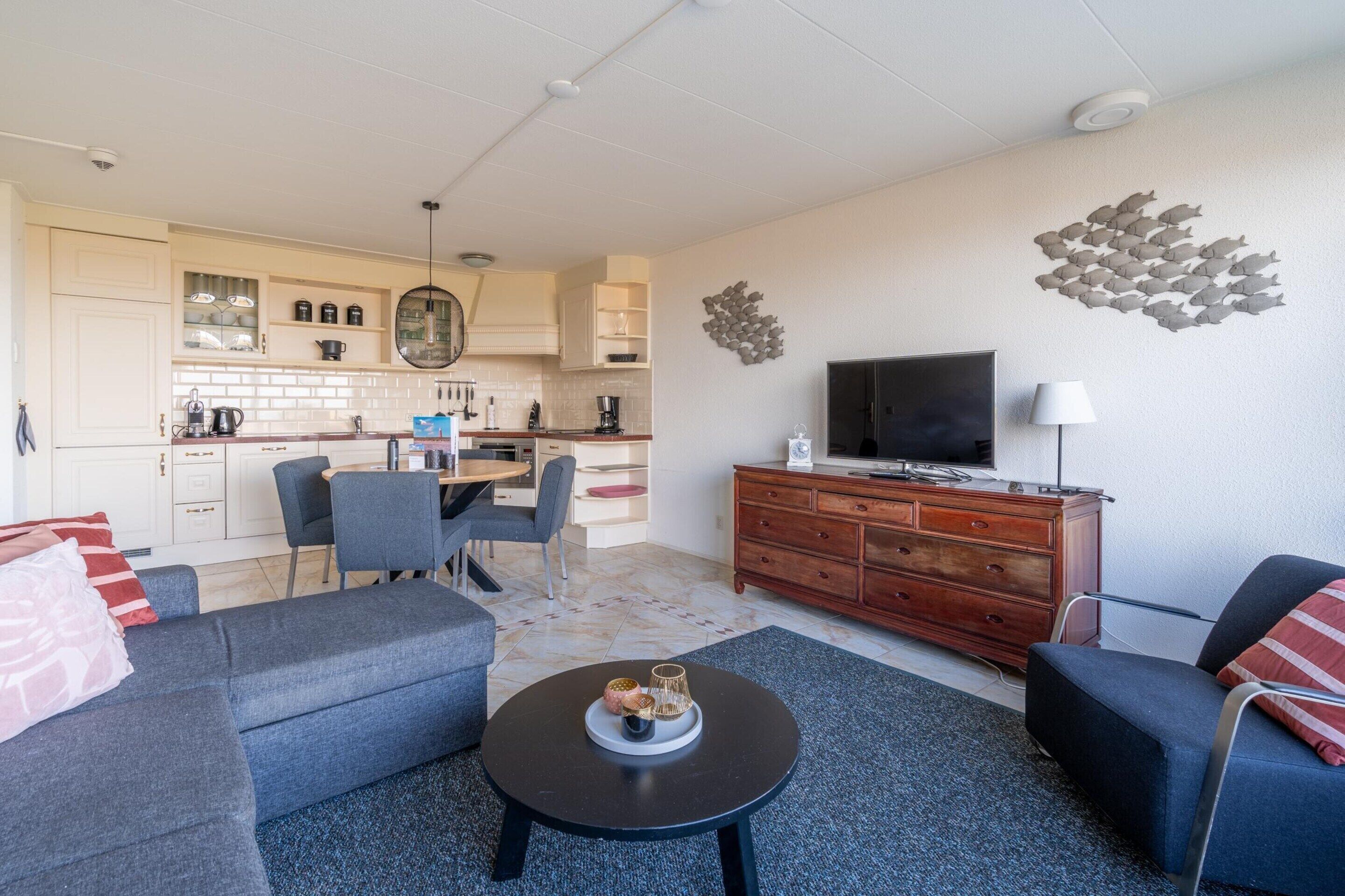Un salon moderne avec un canapé, une table basse et un téléviseur posé sur un meuble en bois.
