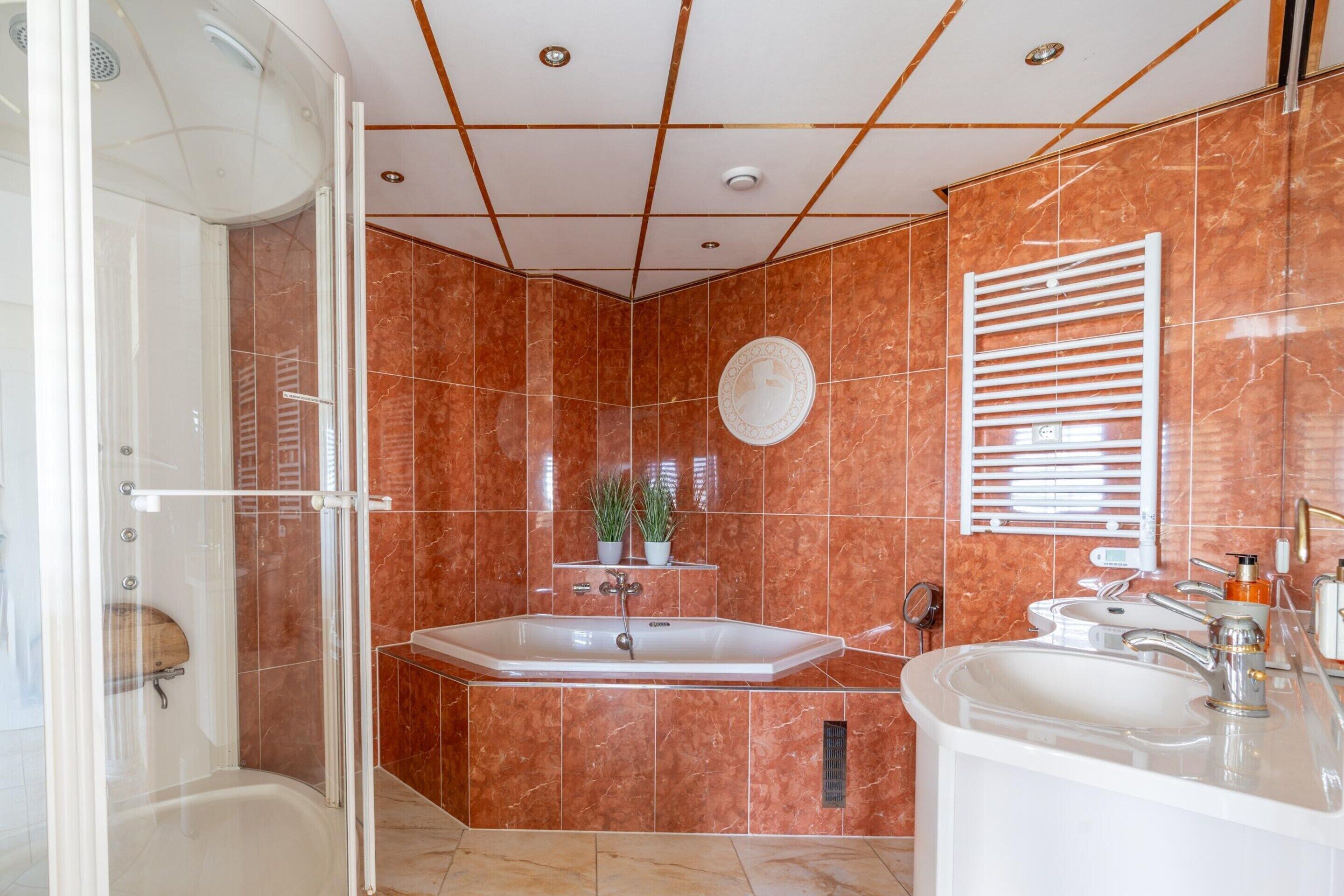 Un baño moderno con ducha de vidrio, bañera independiente y tocador con lavamanos.