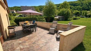 Eine Terrasse im Freien mit Tisch und Stühlen, ein kleiner Tisch mit Tablett und eine Holzkonstruktion.