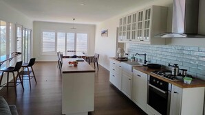 Uma cozinha moderna com armários brancos, uma ilha central e uma área de jantar com cadeiras.