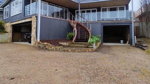 Uma casa moderna de dois andares com varanda coberta, escada em espiral e garagem.