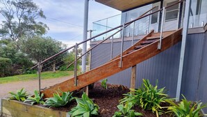 Uma escadaria de madeira leva a um edifício com guarda-corpo de metal.