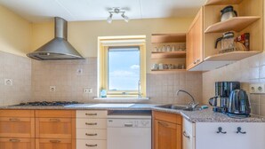 Une cuisine avec des meubles de rangement en bois, un lave-vaisselle, une cuisinière, une fenêtre et une machine à café.