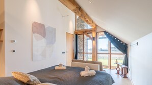 A bedroom with a large bed, a stone wall, and a view of the outdoors. - Modern 6-person Villa With Private Hot Tub - Near Beach & Nature (De Koog)