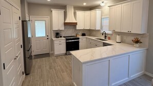 A modern kitchen with white cabinetry, a central island, and a built-in oven.